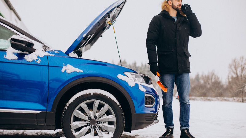 Auto ferma con gelo e uomo in piedi al telefono